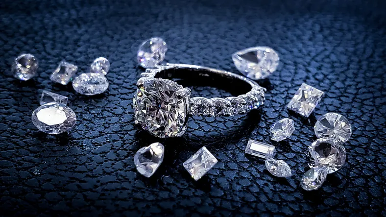 A diamond ring and diamonds are on a blue display table.