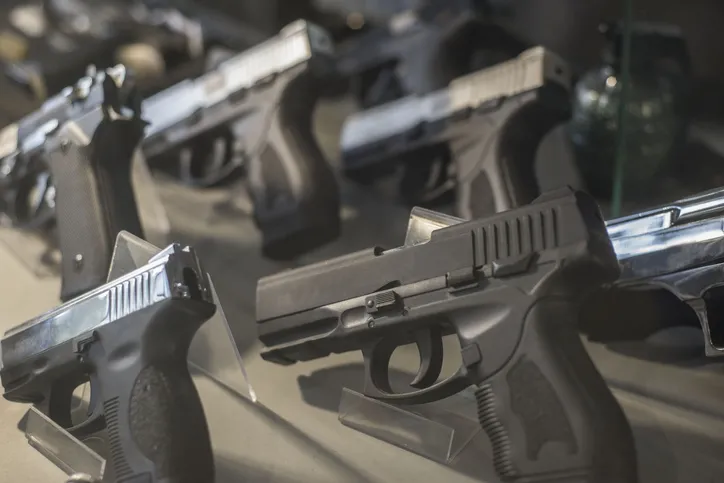 A display of various handguns, in a store, illustrating a scene of gun purchase or selection.