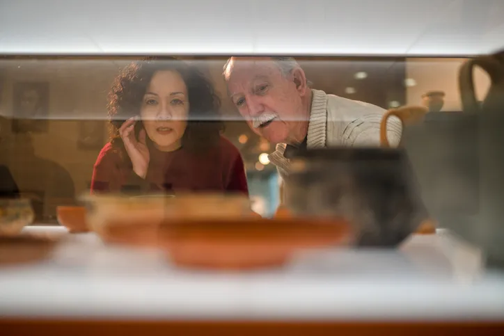 A father and his daughter are looking at collectibles through a retail shop window.