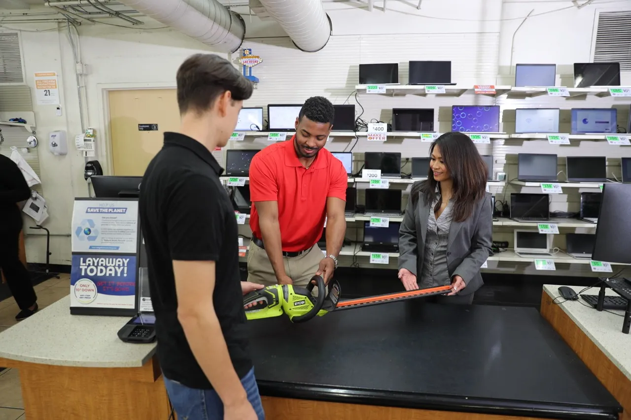 People examining or purchasing a hedge trimmer at a store.