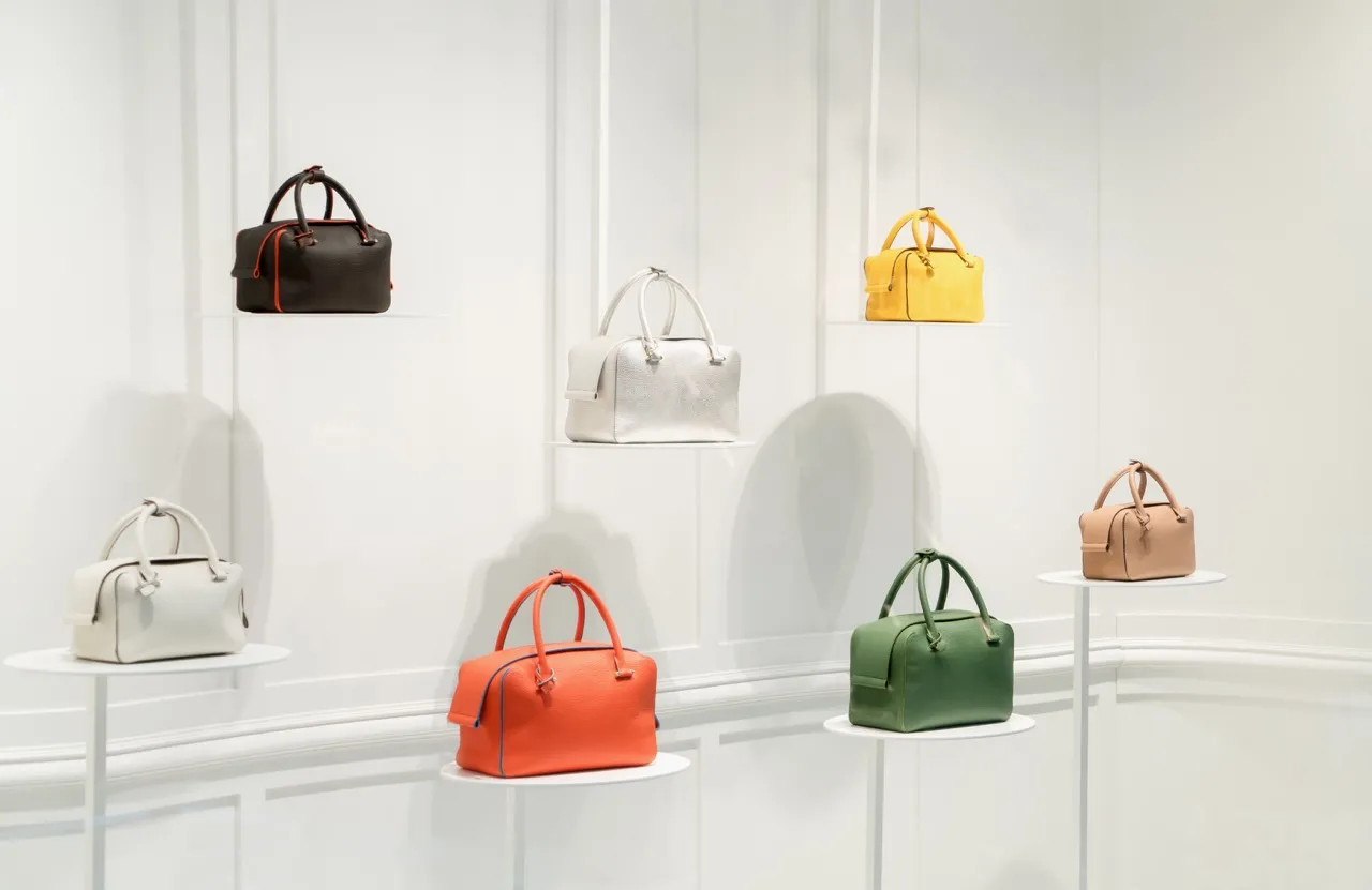 Seven luxury bags are on display in a store.
