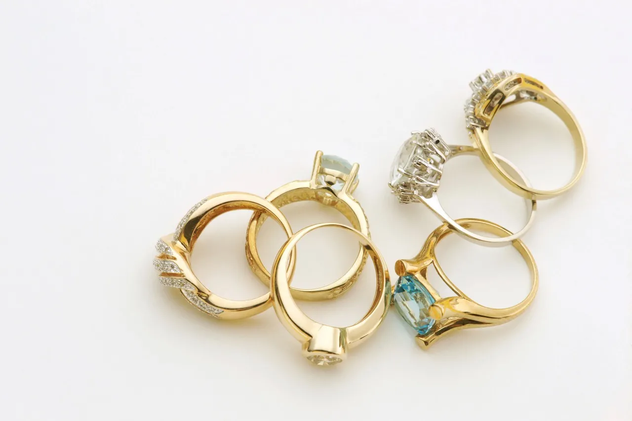 Six diamond rings are laying on a white table.