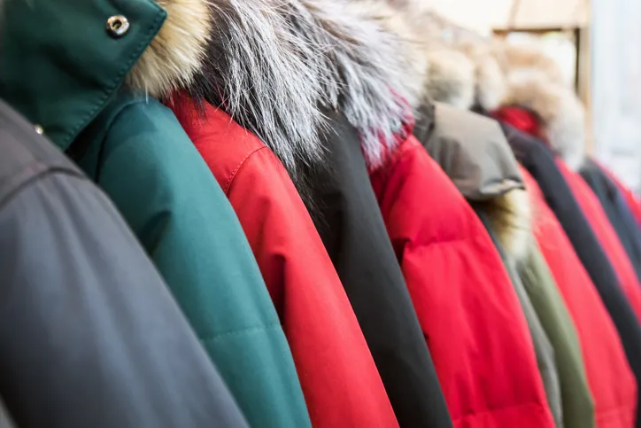 A close up shot of 10 plus winter coats on a rack.
