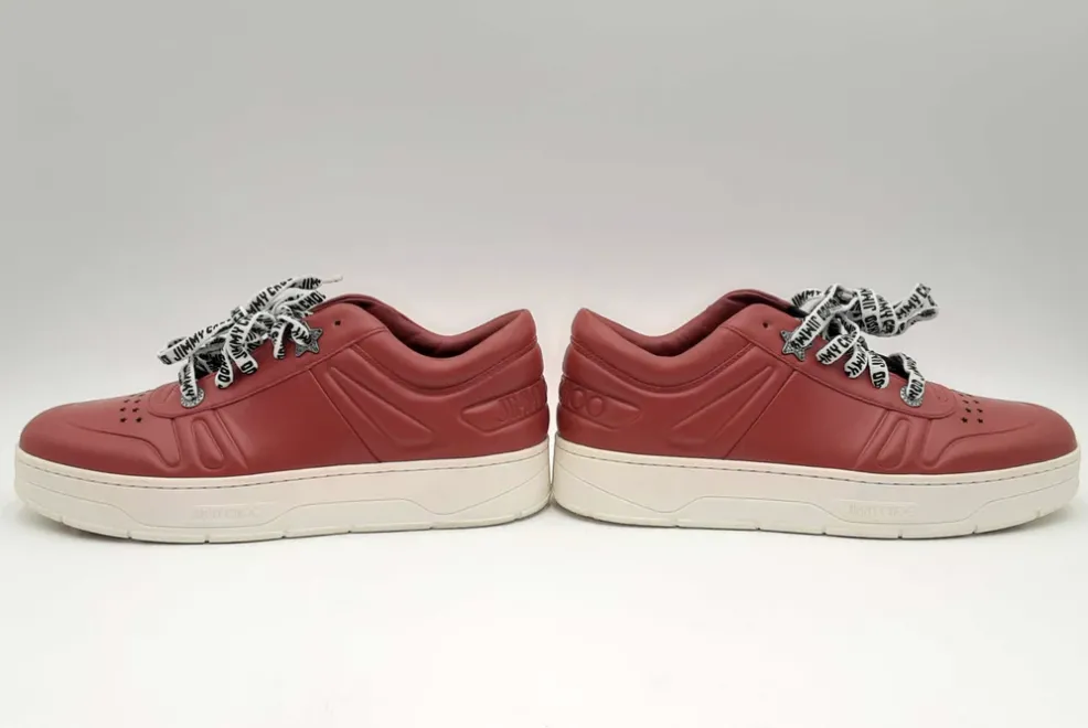 A pair of red Jimmy Choo sneakers with branded laces.