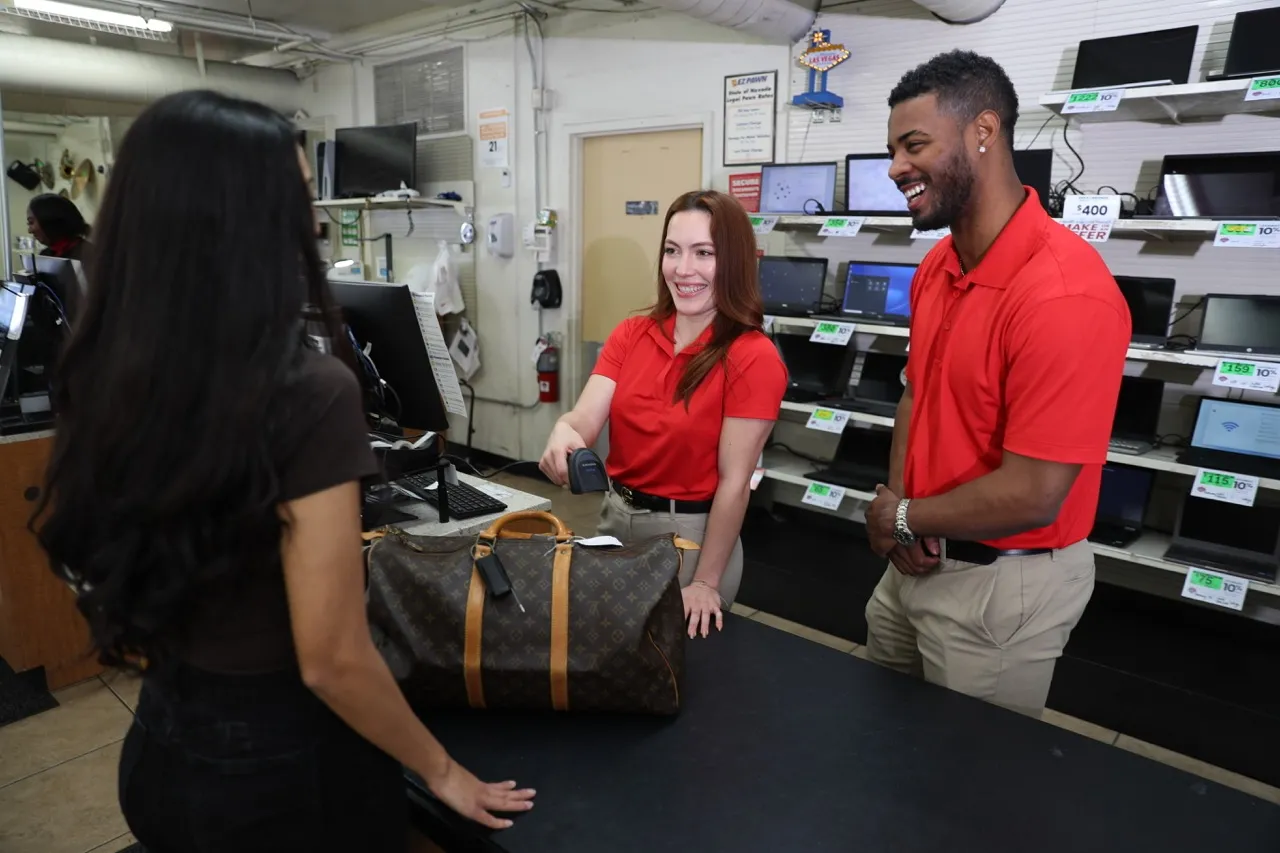 A Louis Vuitton bag being evaluated at a store counter by a sales associate.