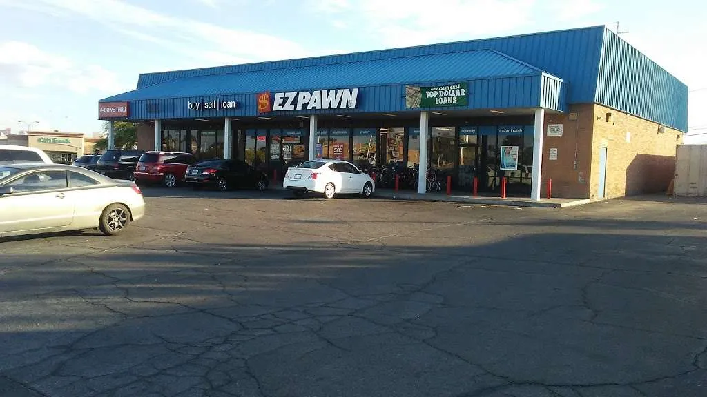 A picture of an EZPAWN store from the parking lot during the daytime. The EZPAWN store is located in a strip mall.