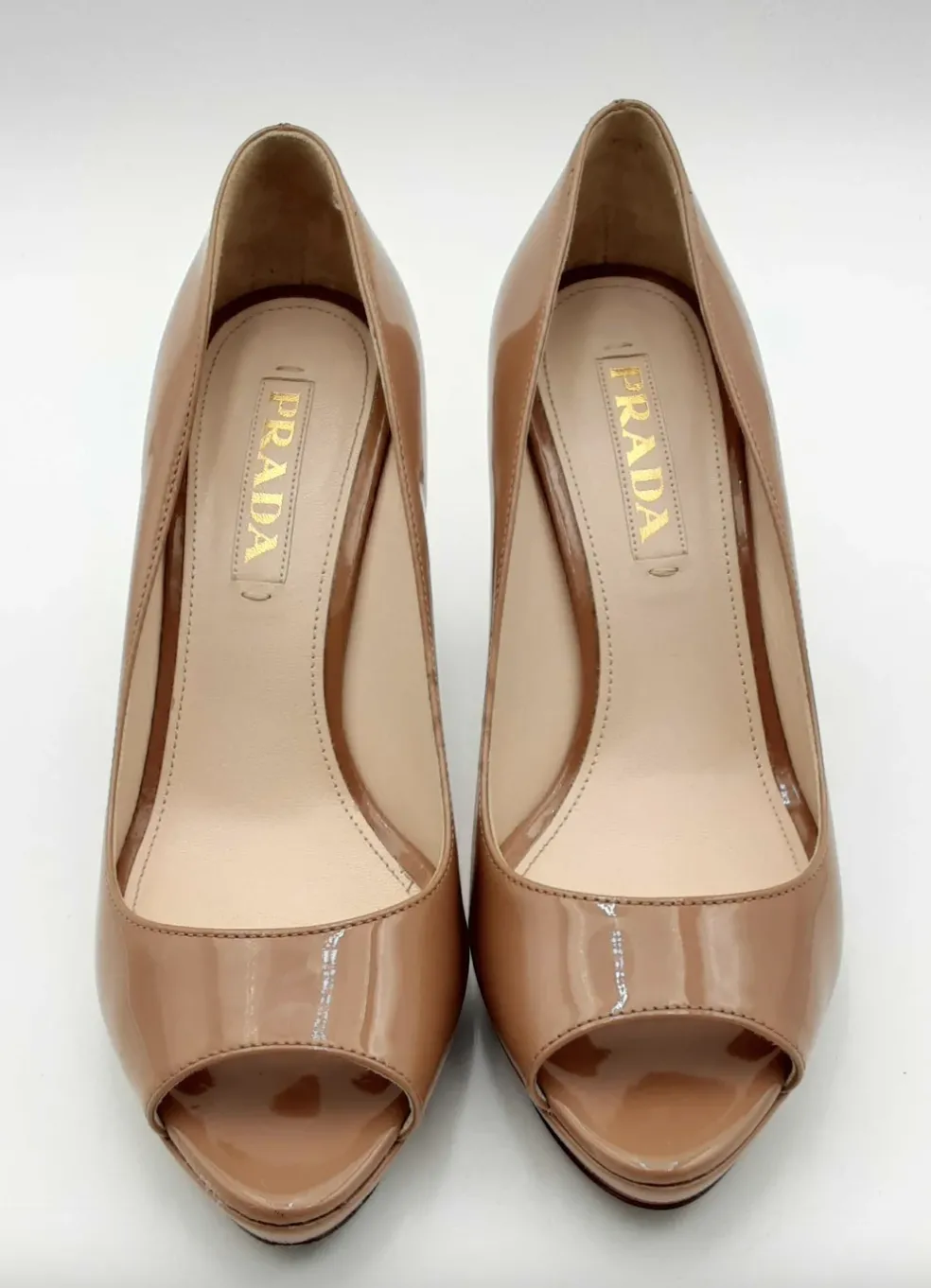 Nude-colored patent leather peep-toe heels by Prada.