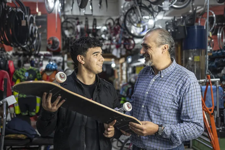 A scene in a store where a customer is examining or purchasing a skateboard.