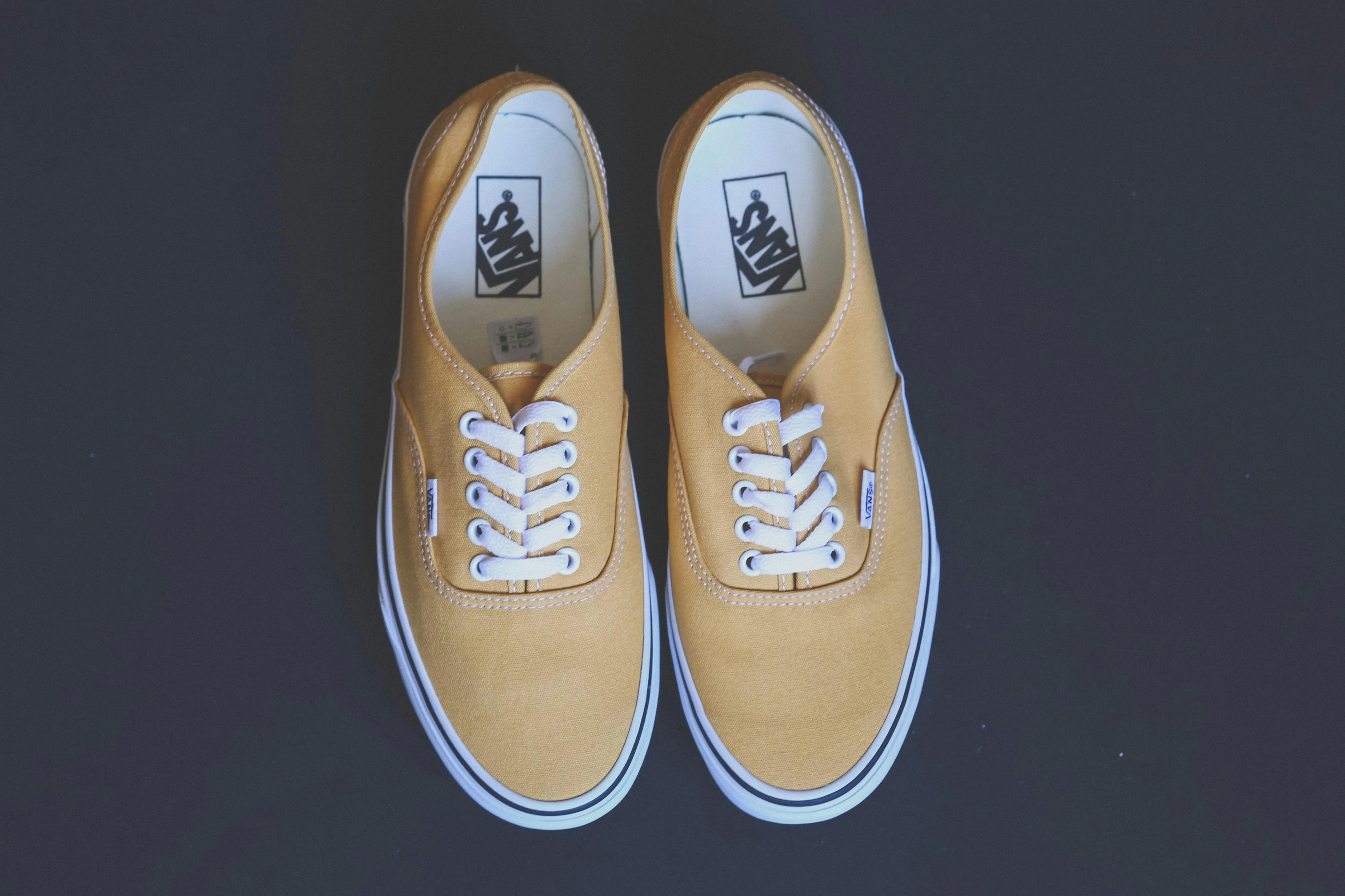 Yellow Vans sneakers, presented on a dark background.