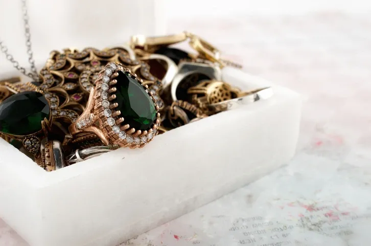 A collection of green vintage jewelry and gemstones are sitting on a jewelry box with the lid open.