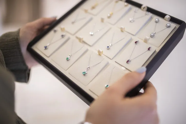 Someone holding a display tray with various pendant necklaces featuring gemstones.