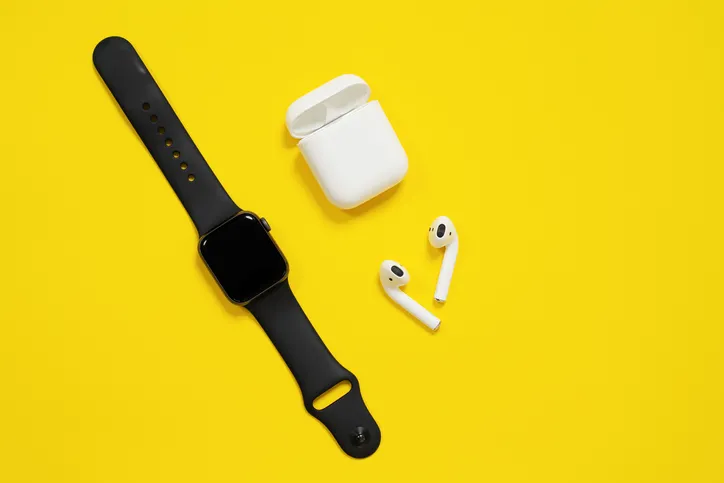 An Apple watch and Airpods are displayed on a yellow background.