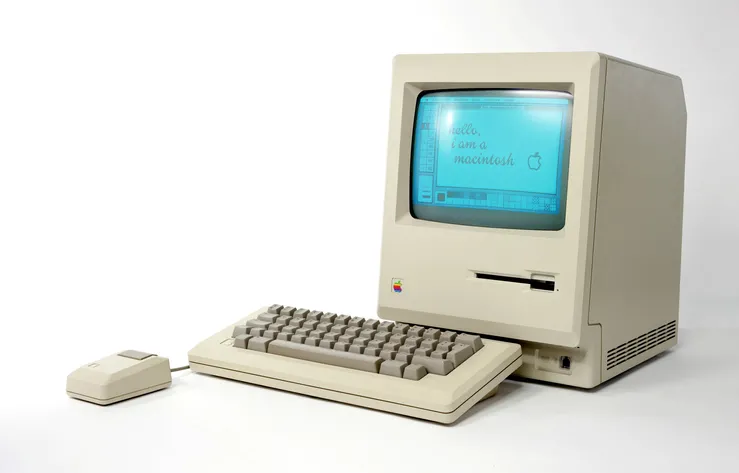 An old Mac desktop computer is on display. The screen is on.